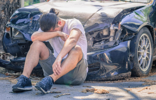 man after sitting in front of car after collision